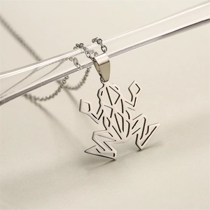 Vue macro d'un pendentif grenouille argenté en acier inoxydable au design origami creux