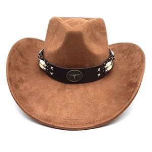 Détail d'un chapeau de cowboy en daim marron avec bande décorative et logo tête de taureau