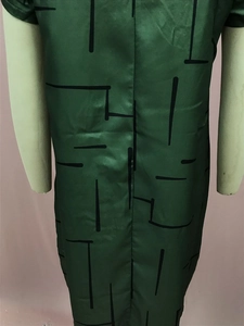 Detail of dark green satin dress featuring black geometric lines and silk-like texture