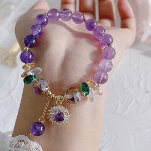 Close-up of a natural purple amethyst bracelet with a flower charm on a woman's wrist
