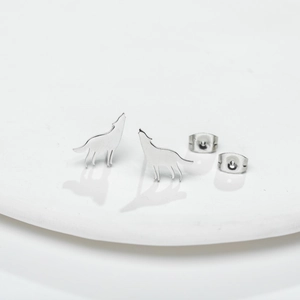 Minimalist silver wolf earrings set in polished metal finish on a white tray
