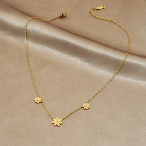Gold plated daisy pendant necklace with three small flowers on a soft silk background