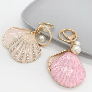 Detailed close-up of shell keychains with pearls and rhinestones on a golden lobster clasp