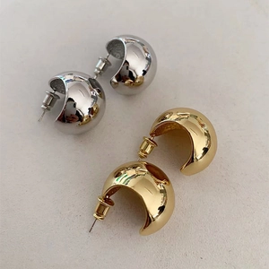 Detailed close-up of polished C-shaped chunky metal earrings in gold and silver finishes
