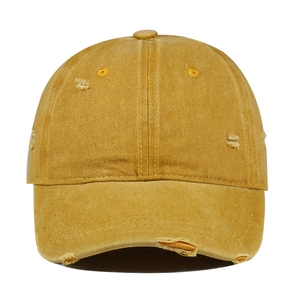 Detail of vintage washed cotton baseball cap with distressed torn edges in mustard yellow