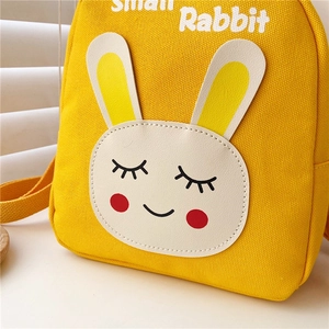 Close-up of yellow canvas backpack showing leather rabbit detail and Small Rabbit text