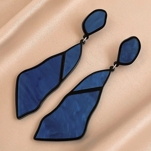 Macro detail of irregular geometric navy blue acrylic earrings on champagne silk
