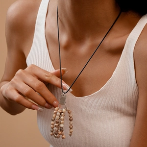 Detail of multi-layer beaded necklace with beige stones on black cord and silver clasp