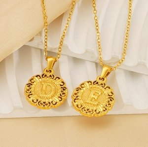 Close-up of vintage gold D and E initial pendants with embossed texture and fine border
