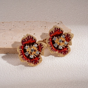 Vintage floral stud earrings with red enamel petals and crystals on beige stone background