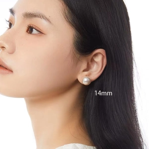 Close-up of 14mm round faux pearl stud earrings worn by a model on a white background