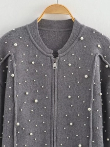 Detail of grey knitted bomber jacket with white pearl beads and silver metal zipper