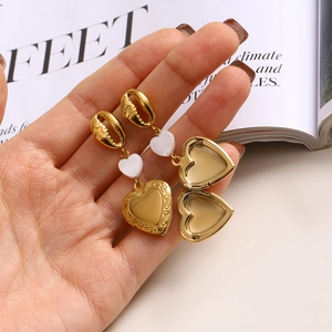 Detail of golden shell heart locket earrings showing open and closed functional design
