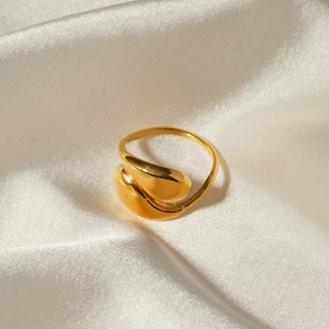 Macro view of golden 18k stainless steel twisted ring on beige silk background