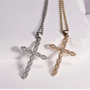 Detail of gold and silver twisted cross necklaces with cubic zirconia on white stone