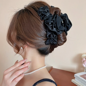 Close-up of black pleated fabric flower hair claw clip on model's elegant hairstyle