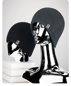 Close-up of fine knit beanies with premium leather brand patch on modern mirror displays