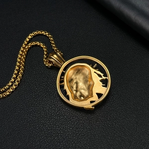 Macro shot of gold stainless steel medallion pendant with relief design on black leather