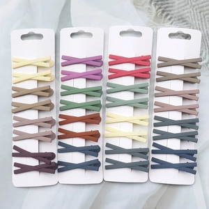 Flat lay of matte pastel geometric cross hair clips in various colors on white fabric