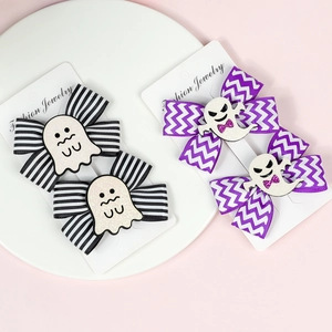 Detail view of two pairs of Halloween hair clips with glitter ghosts and bows on a card