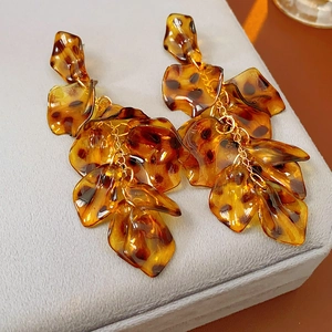 Macro view of leopard print acrylic petal tassels and gold chain detail on earrings