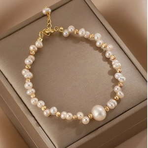 Elegante bracciale di perle d'acqua dolce con perle dorate su portagioie champagne