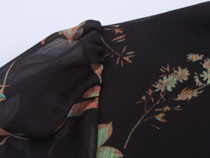 Nahaufnahme des Blumen-Chiffonkleids mit schwarzem transparentem Stoff und Falten-Details