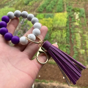 Detail of colorful silicone beaded bracelet keychain with purple tassel and gold clasp