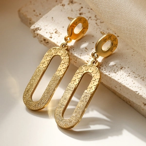Irregular geometric gold titanium earrings with star patterns on a stone base