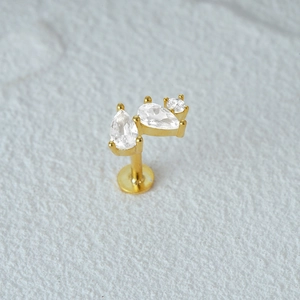 Macro shot of gold-plated flat back cartilage stud with three sparkling zircon stones