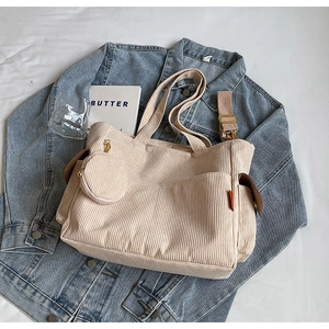 Detail of beige corduroy tote bag with small round pouch on blue denim jacket
