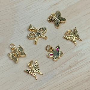 Golden butterfly and bow pendants with colorful crystals on a light wood background