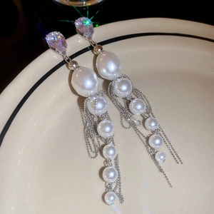 Vue détaillée de boucles d'oreilles à pompons argentés avec perles baroques et cristaux