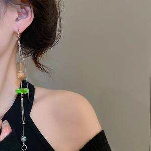Detail of asymmetrical long fringe earrings with green beads and silver ball chains