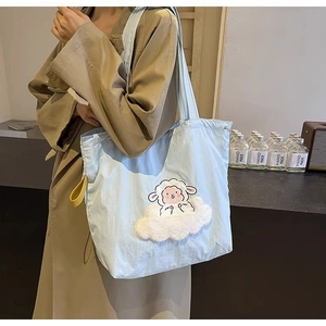 Detail shot of blue canvas tote bag featuring cute 3D sheep and cloud embroidery decoration