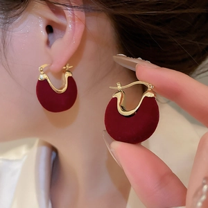 Close-up of red flocked U-shape earrings with gold metal edges for a vintage look