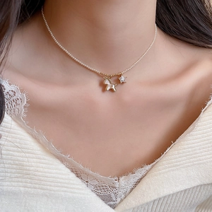 Detail of white pearl necklace with golden pony and star pendant on a woman's collarbone