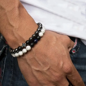Detail of 8mm lava and tiger eye stone bead bracelets with cross charm on male wrist