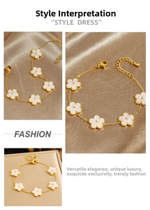 Detail of gold chain bracelet featuring five white flower charms on silk background