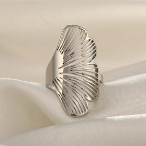 Détail d'une bague feuille de ginkgo argentée avec motif ajouré sur tissu de soie beige