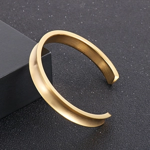 Detail view of gold brushed stainless steel open bracelet with a concave groove design