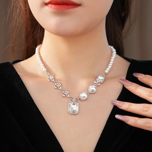 Detail of emerald-cut crystal necklace with silver floral accents and white pearls