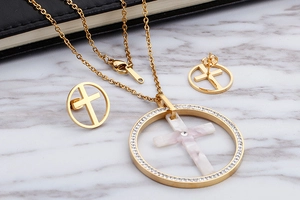 Detailed view of gold jewelry set with marble cross pendants and diamond accents