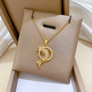 Close-up of a gold dolphin pendant with clear zircons on a beige jewelry cushion