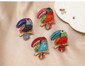 Macro shot of colorful rhinestone toucan bird brooches on luxury champagne satin fabric