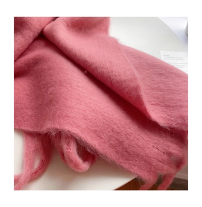 Close-up of soft pink mohair knit scarf with detailed wool texture and long fringe edges