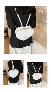 Detailed view of a white heart-shaped backpack with silver metallic logo and zipper