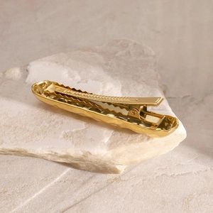 Nahaufnahme der goldenen gehämmerten Haarspange auf natürlichem Steinhintergrund