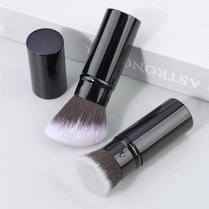 Detailed view of portable retractable powder brush with dual-tone bristles and sleek black cap