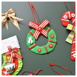 Flat lay of polymer clay Christmas ornaments with wreath, stocking, and candy cane charms
